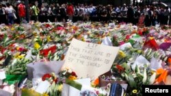 FILE - Members of the public stand behind a note that can be seen amongst floral tributes that have been placed near the cafe where hostages were held for over 16 hours, in central Sydney, Dec. 16, 2014. 