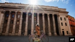 A woman walks in empty Piazza di Pietra square, in Rome, Wednesday, March 18, 2020. For most people, the new coronavirus causes only mild or moderate symptoms. 