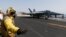 A flight deck crew member is seen giving an 'all clear' before a F/A-18C Hornet takes off from the aircraft carrier USS George H.W. Bush in the Persian Gulf August 12, 2014.