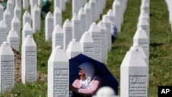 A Bosnian Muslim woman protects herself from the sun during a funeral ceremony for dozens of newly identified victims of the 1995 massacre, at the memorial centre of Potocari near Srebrenica, 150 kms north east of Sarajevo, Bosnia, July 11, 2017. 