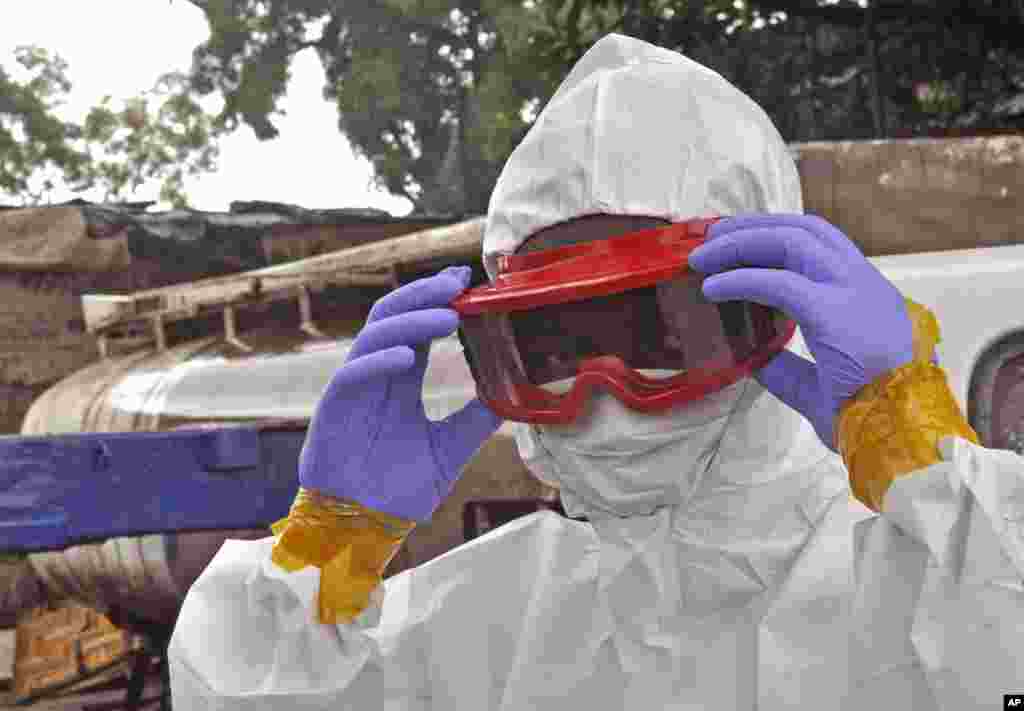 Seorang petugas kesehatan Liberia memakai peralatan pelindung sebelum memindahkan jenazah seorang pria yang diyakini meninggal karena virus Ebola di Monrovia (29/8). (AP/Abbas Dulleh)