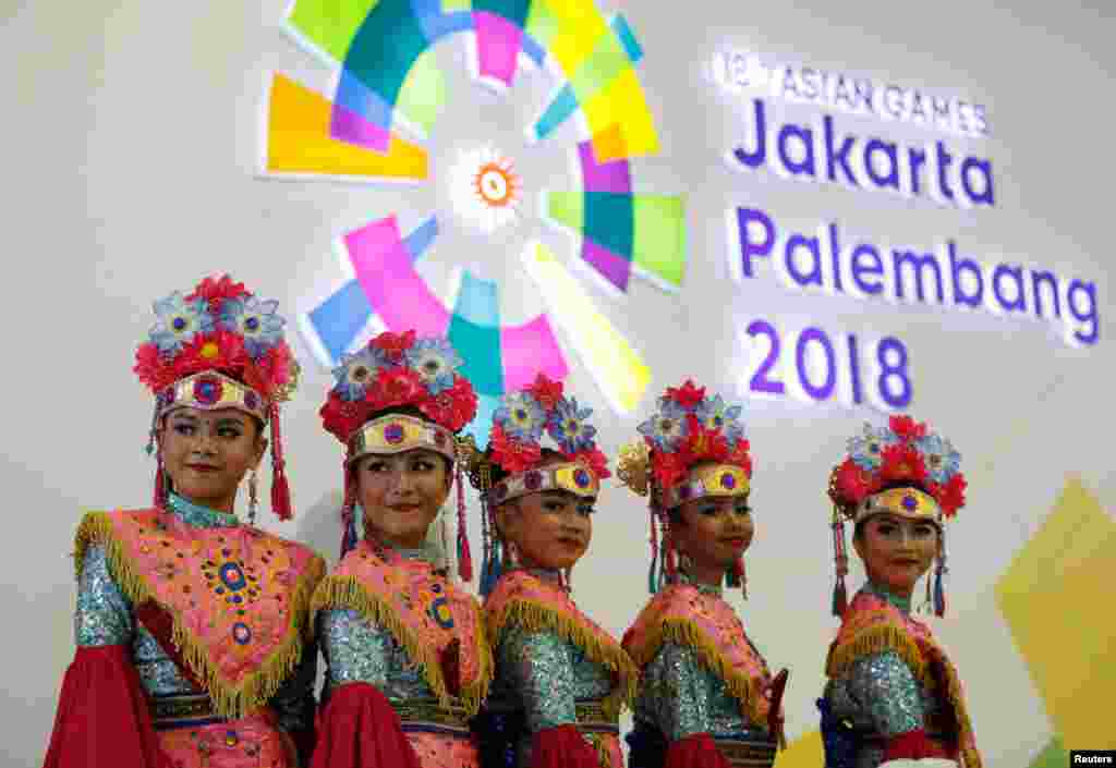 Para penari mengenakan kostum tradisional berdiri di depan logo Asian Games ke-18 di kompleks Gelora Bung Karno, Senayan, Jakarta, 16 Agustus 2018.&nbsp; (REUTERS/Issei Kato)