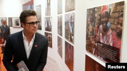 FILE - Actor Brad Pitt looks at photographs at a fringe event of a summit to end sexual violence in conflict in London.