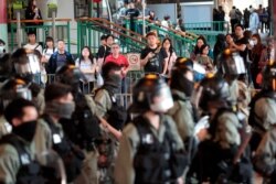 People look on as a riot police officers patrol in anticipation of protests in Tuen Mun area in Hong Kong, Nov. 10, 2019.