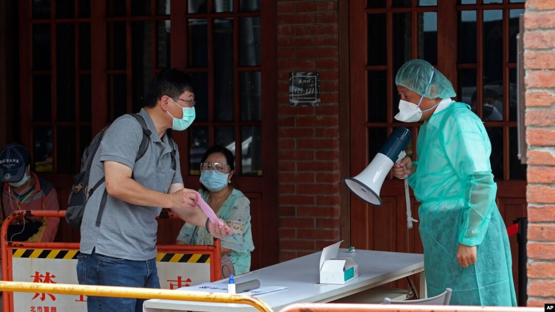 Medical personnel wearing protective gear, guide people at a rapid coronavirus testing center after the infection alert rose to level 3 in Taipei, Taiwan, May 18, 2021.