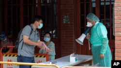Medical personnel wearing protective gear, guide people at a rapid coronavirus testing center after the infection alert rose to level 3 in Taipei, Taiwan, May 18, 2021.