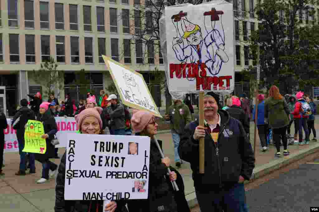 Protesters hold up signs ahead of the Women's March on Washington in downtown Washington, D.C., one day after Donald Trump's inauguration as President of the United States of America. January 21, 2017 (B. Allen / VOA)