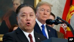 FILE - Broadcom CEO Hock Tan speaks while U.S. President Donald Trump listens, in background, during an event at the White House in Washington, Nov. 2, 2017. 