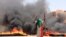 FILE - A protester wearing a Sudanese flag flashes victory signs near army headquarters in Khartoum, Sudan, June 3, 2019. A military assault left dozens of protesters dead that day, and press freedom suffered a blow as well, journalists say.