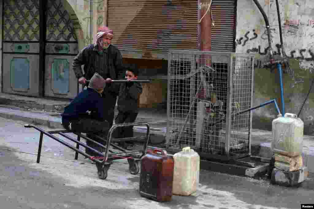 Residents push a lever to fill water containers in Douma, Syria.