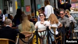 Warga Inggris menikmati suasana dengan makan di sebuah restoran di South Bank, saat pemerintah melonggarkan pembatasan COVID-19 di London (foto: dok). 