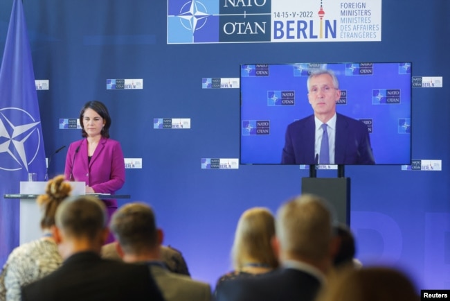 German Foreign Minister Annalena Baerbock, stands next to NATO Secretary General, Jens Stoltenberg, seen on a screen speaking during a news conference at a NATO meeting in Berlin, Germany May 15, 2022. (REUTERS/Michele Tantussi)