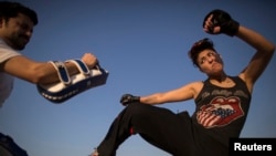 Interior designer Zahra Afridi (R) kicks a punching bag during a kickboxing training session at her home in Islamabad February 10, 2014. Afridi runs her own interior design company. Her most recent project was a Classic Rock Coffee cafe in Islamabad. Thou