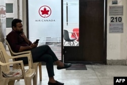 A man checks his mobile outside an Air Canada office in New Delhi on September 20, 2023. India told its citizens to avoid traveling to parts of Canada, following an allegation that India was involved in the killing of a Sikh separatist near Vancouver. (Photo by Arun SANKAR / AFP)