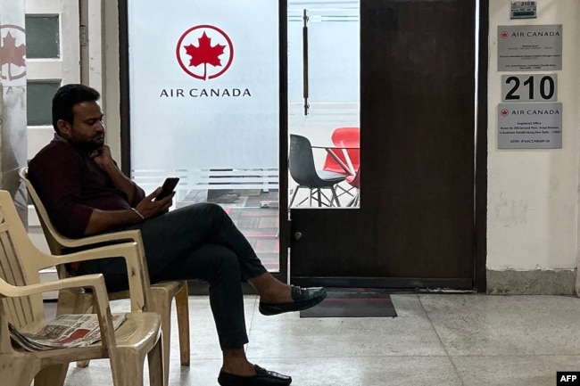 A man checks his mobile outside an Air Canada office in New Delhi on September 20, 2023. India told its citizens to avoid traveling to parts of Canada, following an allegation that India was involved in the killing of a Sikh separatist near Vancouver. (Photo by Arun SANKAR / AFP)