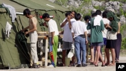 Des migrants se préparent le matin, dans le camp de réfugiés situé sir l'île australienne de Nauru, le 21 septembre 2001.