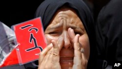 Seorang perempuan Mesir menyerukan slogan-slogan anti-Presiden Morsi, memegang kartu yang bertuliskan "pergi" dalam protes di Lapangan Tahrir, Kairo (28/6).