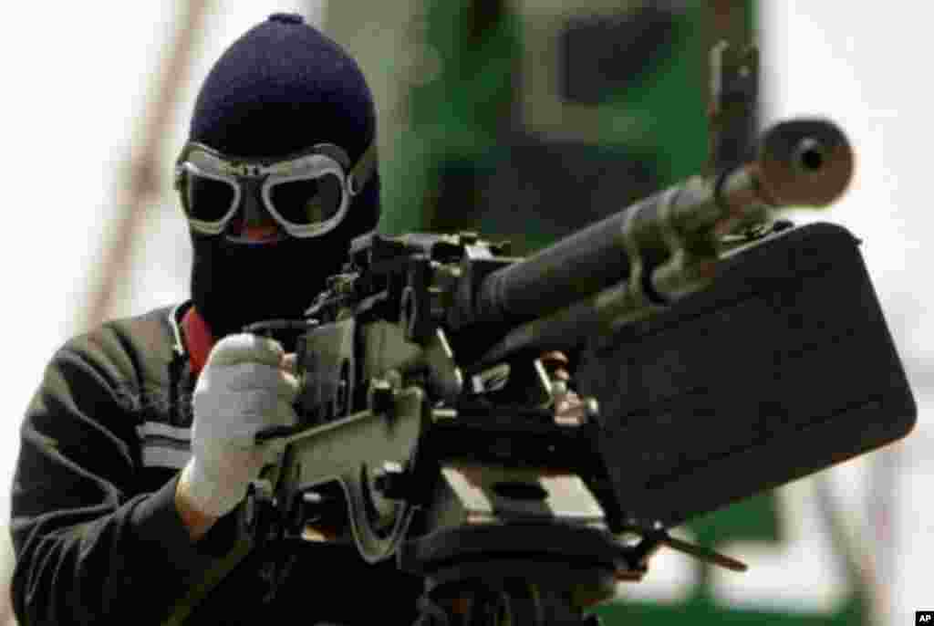 A Libyan rebel wearing woolen gloves and mask mans a heavy machine gun as he drives into the battle frontline at the western gate of the strategic town of Ajdabiya on April 23, 2011. (AFP image)