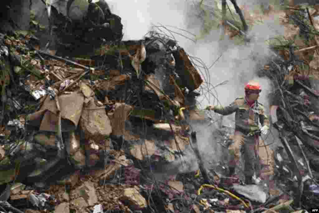 A firefighter stands in the rubble of a building that collapsed in downtown Rio de Janeiro, Brazil, Friday Jan. 27, 2012. The building collapsed on Wednesday, killing at least 9 people and at least 16 are still missing. (AP Photo/Victor R. Caivano)