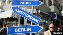 People walk past symbolic road signs showing Europe states under the "visa free" sign in Tirana November 7, 2010. The Council of EU interior ministers is expected to approve visa free travel for the citizens of Albania and Bosnia on November 8, 2010…