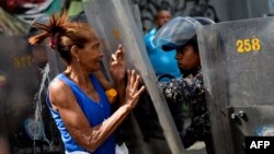 Seorang demonstran bentrok dengan polisi anti huru-hara dalam unjuk rasa di Caracas, Kamis (28/12). 