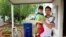Osvaldo Salas, 29, stands with his son outside their home in suburban Phoenix on Wednesday, March 18, 2020. Salas, who isn't proficient in English, says he's disappointed state authorities haven't posted any information on the coronavirus in Spanish…
