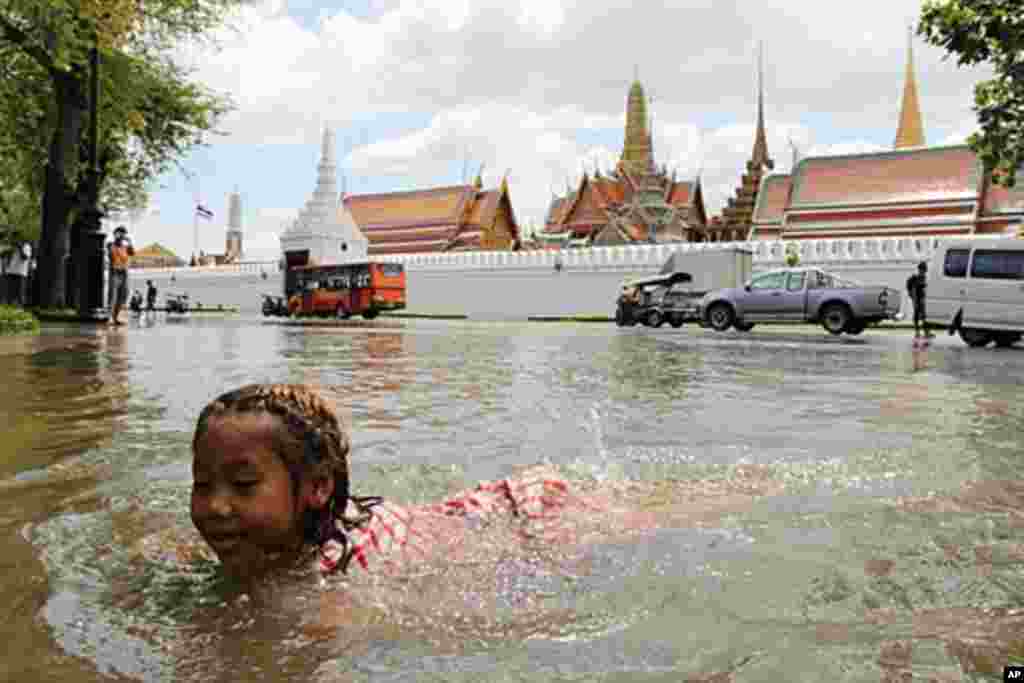 A girl swims in the floodwater in front of Bangkok's Grand Palace in a riverside neighborhood, Thailand, October 28, 2011. (VOA)