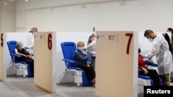 FILE - Women receive the Moderna vaccine against the coronavirus disease at the Music Auditorium in Rome, Italy, April 14, 2021. 