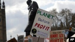 ARSIP – Para pengunjuk rasa berunjuk rasa di depan patung Winston Churchill dengan mengusung poster di sekitar Gedung Parlemen di London, Inggris, 12 April 2019 (foto: AP Photo/Kirsty Wigglesworth, arsip)