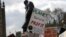 FILE - Climate change demonstrators hold banners in front of the Winston Churchill Statue during a protest near Parliament in London, April 12, 2019. 