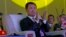 FILE - Wanda Chairman Wang Jianlin applauds in front of the logo for Dalian Wanda Group during an event at a hotel in Beijing, China, June 19, 2013.