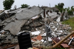 A man walks on the rubble of a collapsed hotel the morning after Tropical Storm Grace swept over Port Salut, Haiti, Aug. 17, 2021, three days after a 7.2 magnitude quake.