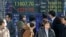People look at an electronic stock board of a securities firm in Tokyo, Feb. 25, 2013. 