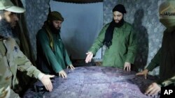 FILE -- This undated photo released by a militant group in 2016, shows Abu Mohammed al-Golani of the militant Levant Liberation Committee and the leader of Syria's al-Qaida affiliate, second right, discussing battlefield details with field commanders.