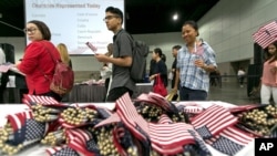 FILE - Immigrants pick flags as they arrive to take their citizenship oath during naturalization ceremonies at a U.S. Citizenship and Immigration Services (USCIS) ceremony in Los Angeles, Sept. 20, 2017.