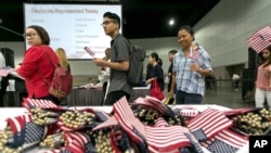 FILE - Immigrants pick flags as they arrive to take their citizenship oath during naturalization ceremonies at a U.S. Citizenship and Immigration Services (USCIS) ceremony in Los Angeles, Sept. 20, 2017.