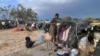 Des migrants d'Afrique subsaharienne à côté d'abris de fortune dans le camp al-Amra, à la périphérie de la ville portuaire tunisienne de Sfax, le 23 avril 2024. 