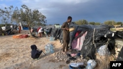 Des migrants d'Afrique subsaharienne à côté d'abris de fortune dans le camp al-Amra, à la périphérie de la ville portuaire tunisienne de Sfax, le 23 avril 2024. 