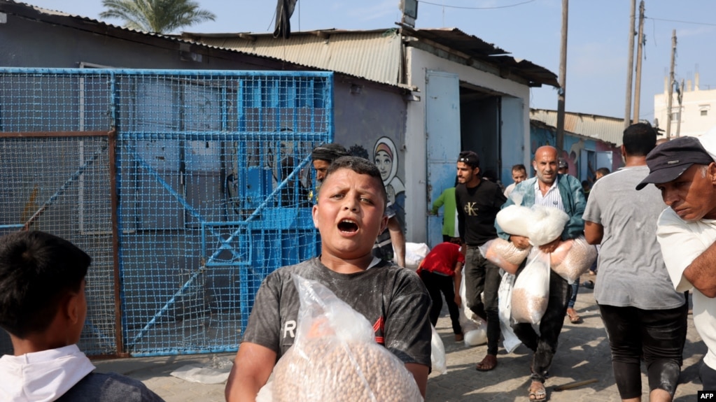 2023年10月28日，在代尔巴拉赫，巴勒斯坦人涌入联合国运营的一个援助供应中心，该中心向流离失所的家庭分发食品，此前以色列呼吁加沙北部100多万居民向南迁移，以确保安全.(法新社)(photo:VOA)
