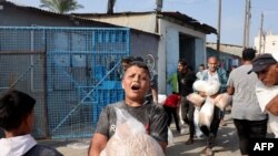 2023年10月28日，在代尔巴拉赫，巴勒斯坦人涌入联合国运营的一个援助供应中心，该中心向流离失所的家庭分发食品，此前以色列呼吁加沙北部100多万居民向南迁移，以确保安全.(法新社)