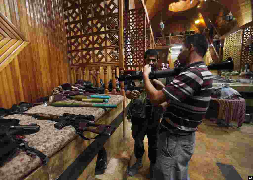 A Free Syrian Army soldier, right, shows his comrade how to use an RPG at a Turkish bath or Turkish Hamam which the rebels took as a base and rest position, in Aleppo, Syria, Sept. 24, 2012.