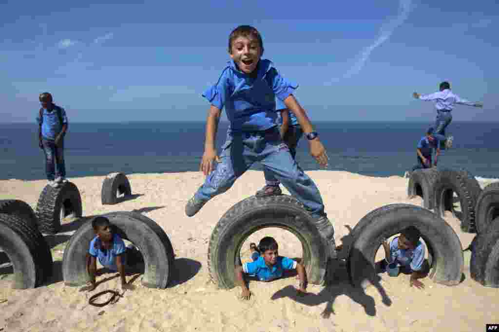 Palestinian school children play with tyres on a Gaza beach on in Deir al-Balah.