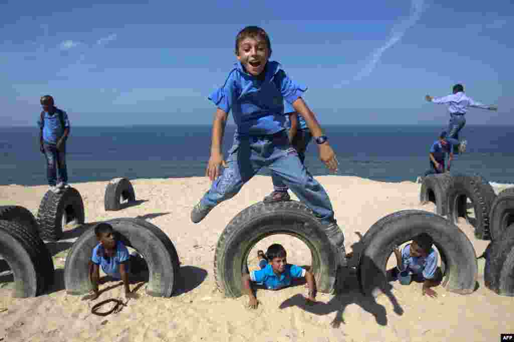 Anak-anak sekolah Palestina bermain dengan ban di pantai di kota Deir al-Balah, Jalur Gaza.