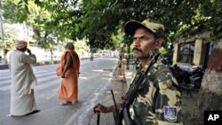 An Indian paramilitary soldier stands guard as Hindu holy men wait outside the Lucknow High Court before the Ayodhya verdict in Lucknow, India, 30 Sept. 2010