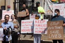 FILE - People from a coalition of housing justice groups hold signs protesting evictions during a news conference outside the Statehouse, July 30, 2021, in Boston.