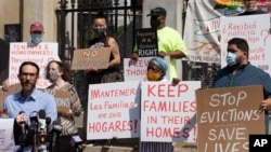 People from a coalition of housing justice groups hold signs protesting evictions during a news conference outside the Statehouse, July 30, 2021, in Boston. 