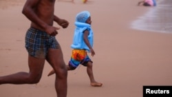 FILE - A child runs as beach-goers enjoy New Year's Day in the rain, on the beach in Durban, South Africa January 1, 2024. (REUTERS/Rogan Ward)