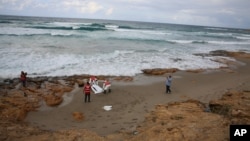 FILE - In this Oct. 25, 2015 photo, Red Crescent workers prepare to carry the lifeless body of a migrant, in the port city of Khoms, Libya. The International Organization for Migration calls death by asphyxiation on board smugglers’ boats sailing from Libya to Italy a horrific new trend. 