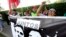 A woman shouts slogans against Peru's former president Alan Garcia outside the residence of Uruguay's ambassador to Peru, behind a sign showing an image of Garcia and Keiko Fujimori, in Lima, Peru, Nov. 18, 2018.