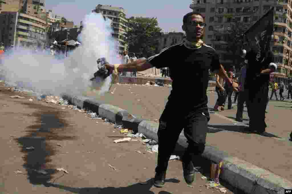 An Egyptian protester throws back a tear gas canister towards the riot police during clashes near the U.S. Embassy in Cairo, September 14, 2012.